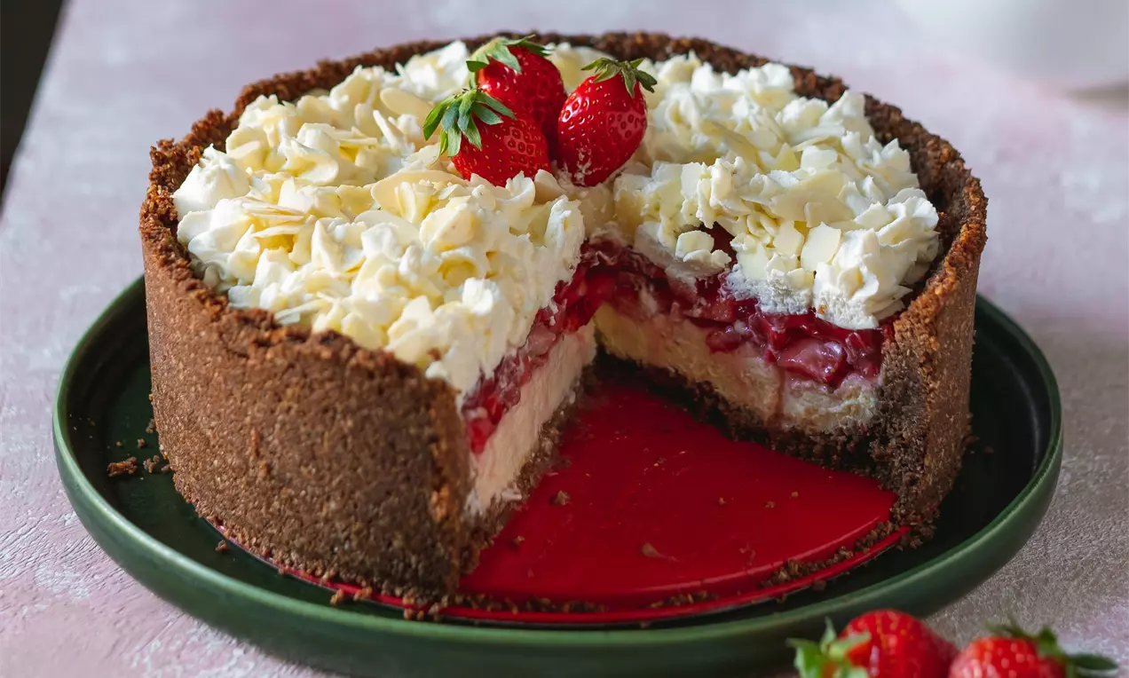 Trojvrstvová jahodová torta s čokoládovým sušienkovým okrajom, vrstvou vanilkového krému, jahodovej polevy a šľahačky, ozdobená čerstvými jahodami